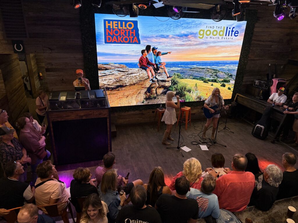 Hello North Dakota Banner with a band playing in front of it.